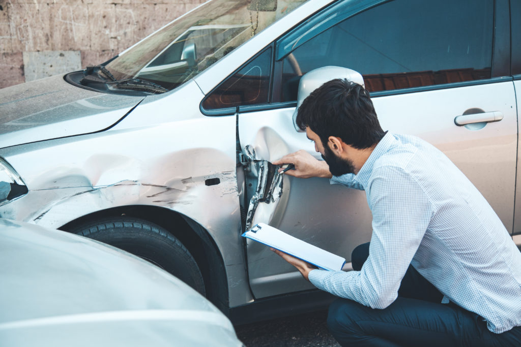 expert examinant une voiture accidentée